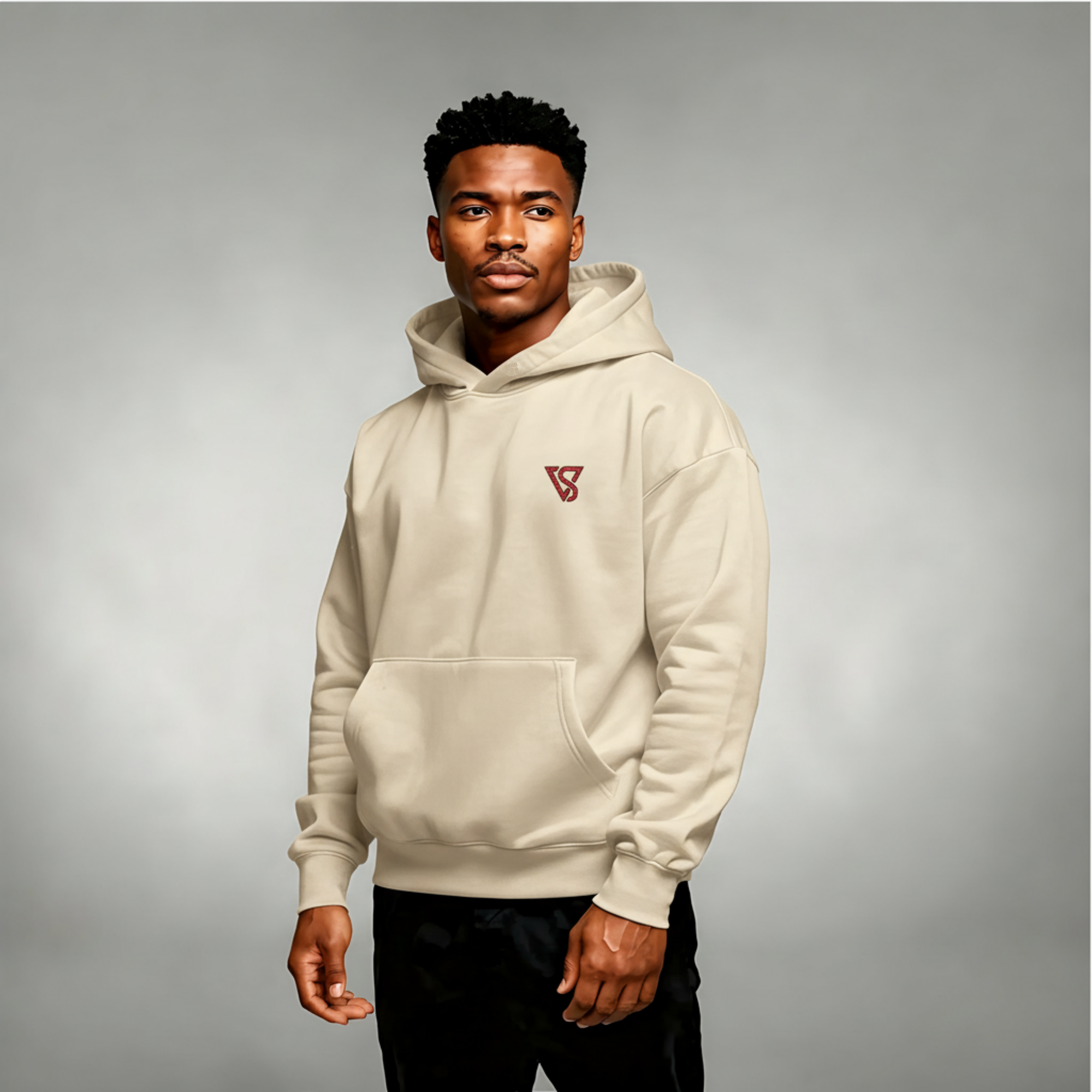 Man wearing a beige hoodie with a logo on a gray background