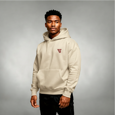 Man wearing a beige hoodie with a logo on a gray background