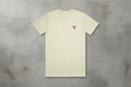 Beige t-shirt with a small red logo on a concrete background